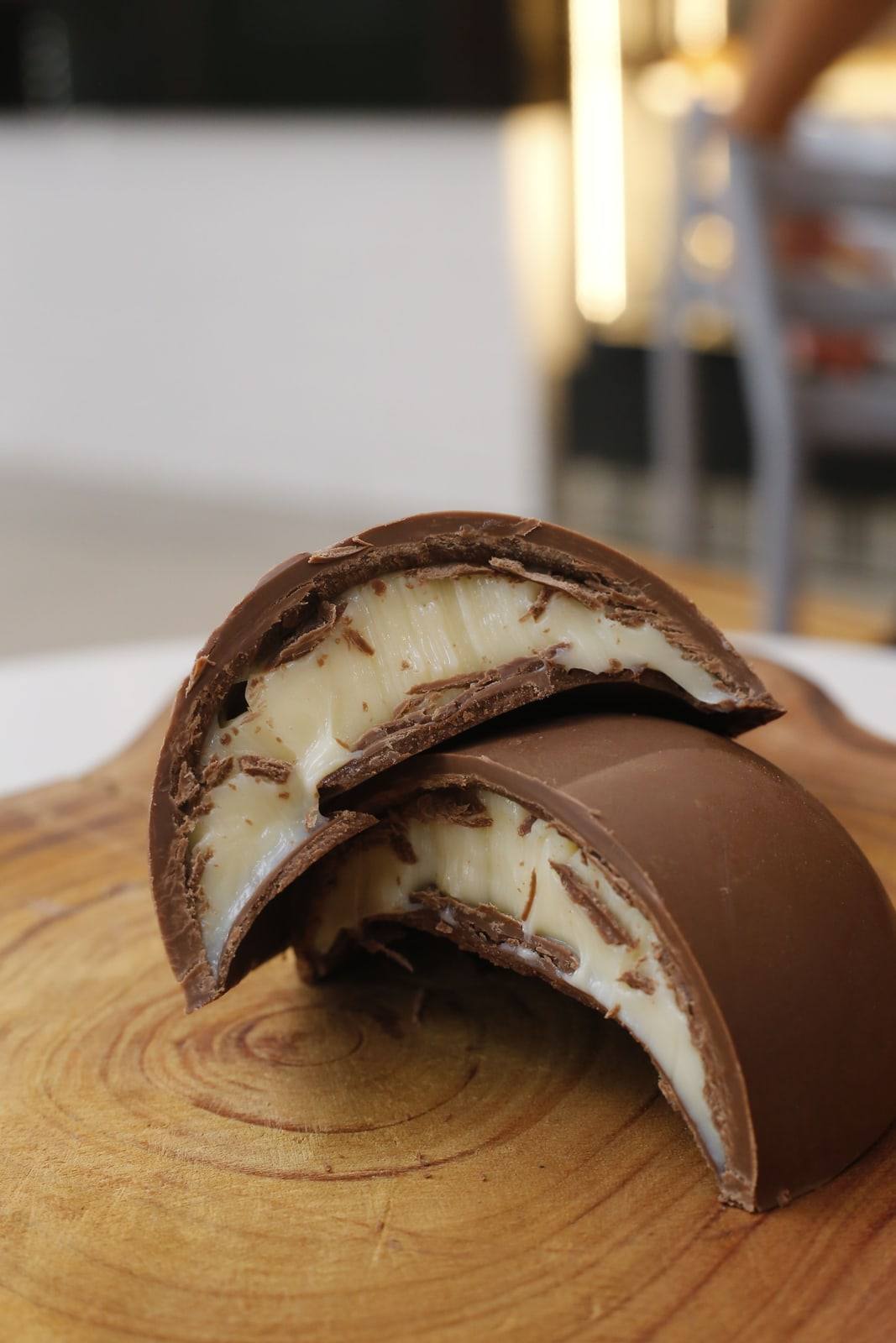 Ovo de Páscoa artesanal da Tia Célia cortado ao meio, mostrando a casca grossa de chocolate e o recheio cremoso.